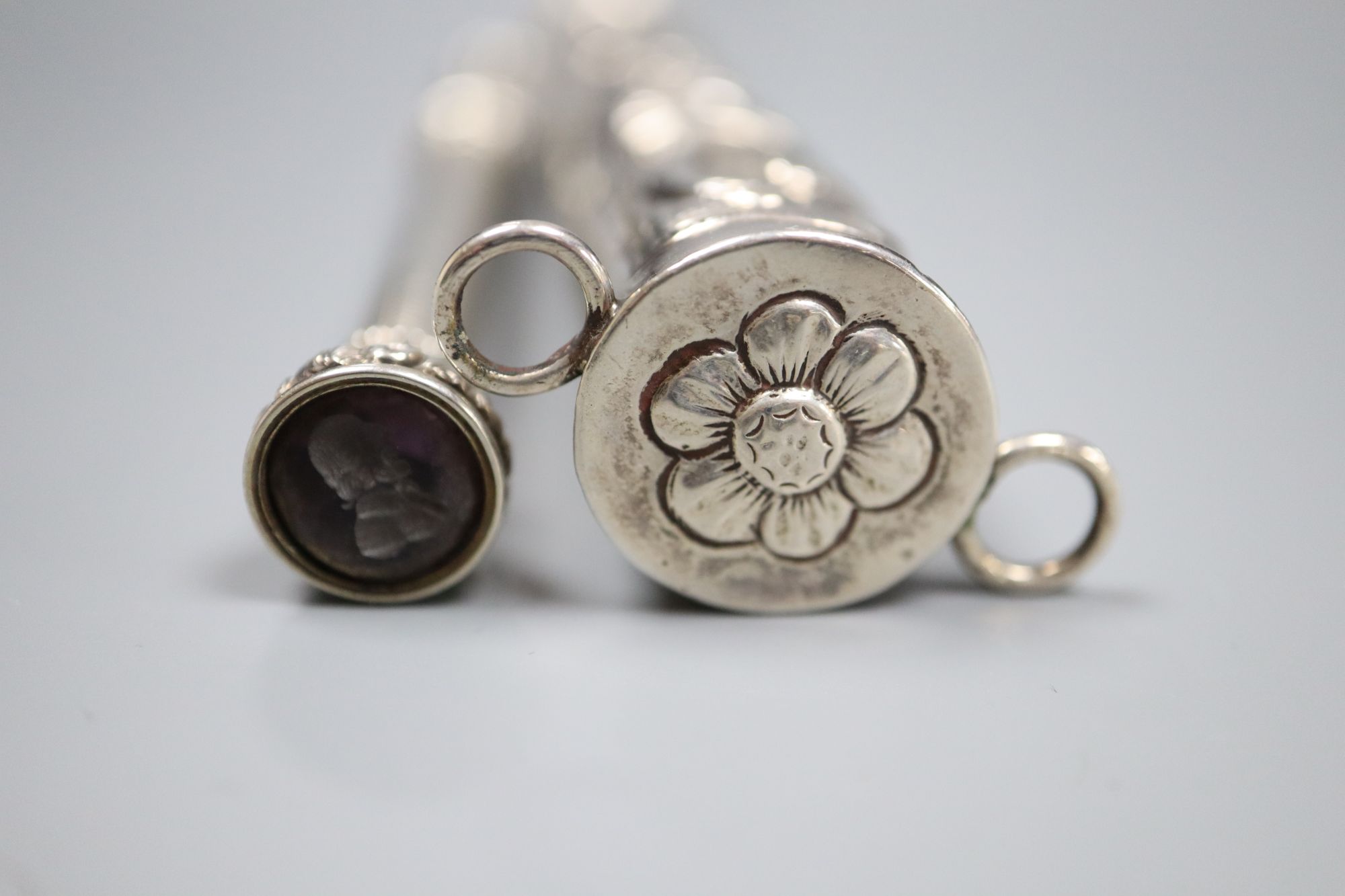 Two white metal propelling pencils, including engine turned with amethyst coloured intaglio set terminal, 93mm.